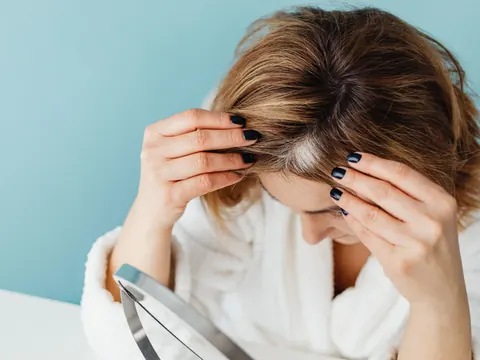 A woman checking her hair and scalp in a mirror