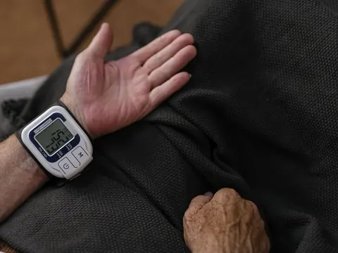A wrist blood pressure monitor on an older man's wrist