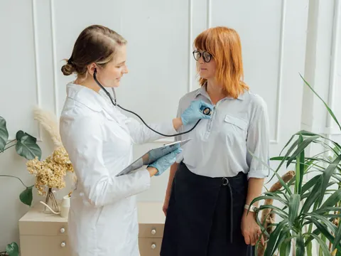 A doctor listening to a woman's heart with a stethoscope