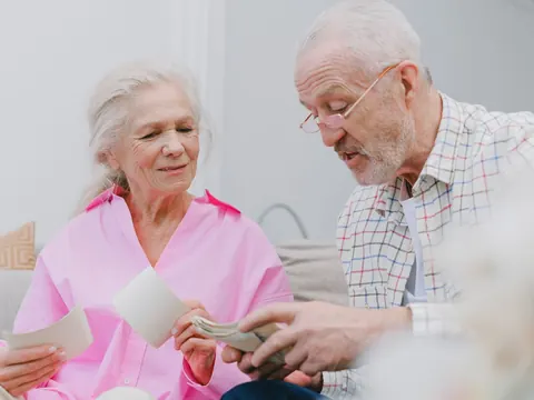 An older couple looking at old photographs on the sofa