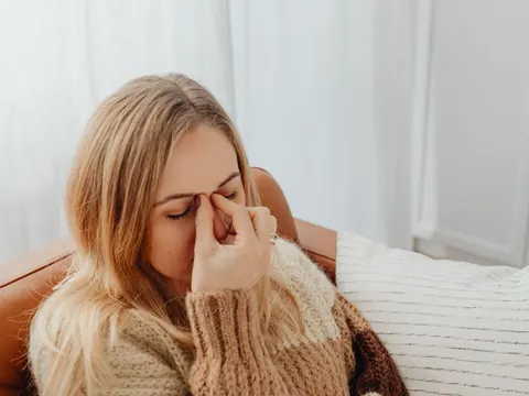 A woman with sinus pain pressing the bridge of her nose