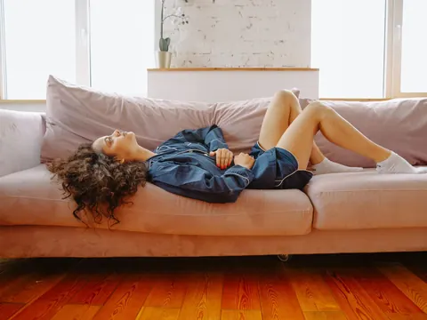 A woman with lower stomach pain on the sofa