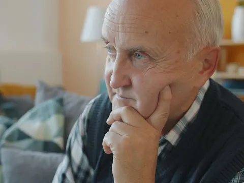 An older man deep in thought in his living room