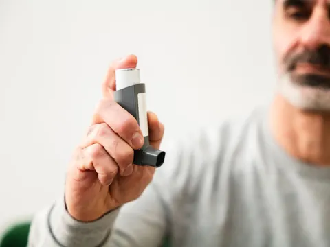 A man holding an asthma inhaler