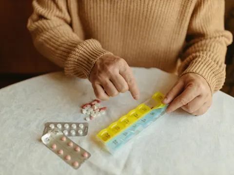Older hands filling a weekly pill box