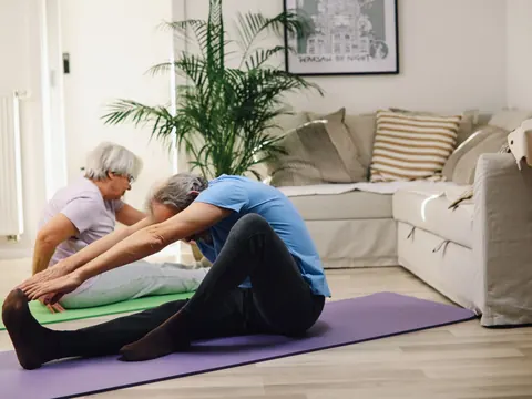 An older couple stretching in their living room