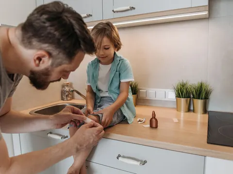A father putting a plaster on his son's knee