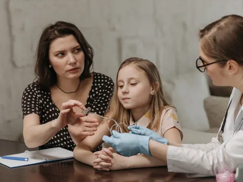 A doctor talking with a mother and daughter at the family table