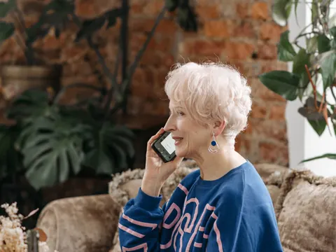 An older woman on the phone on her sofa