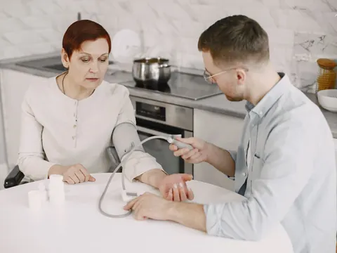 Blood pressure measured on a woman at her kitchen table