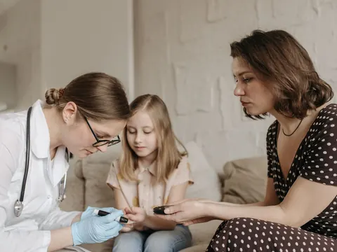 A child examined on the sofa, the mother beside her