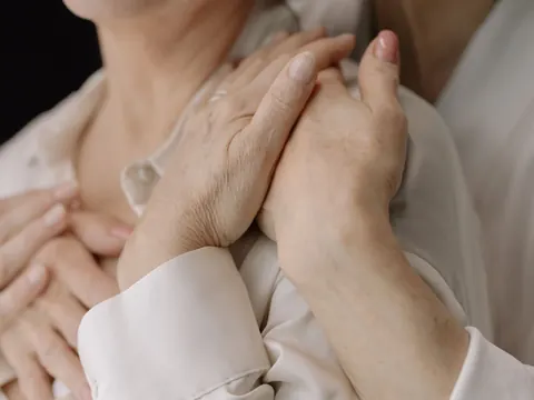 A carer holding an older woman's hands