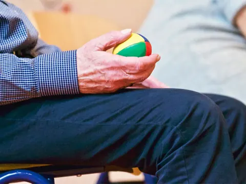 An older man exercising his hand with a ball, for rehabilitation