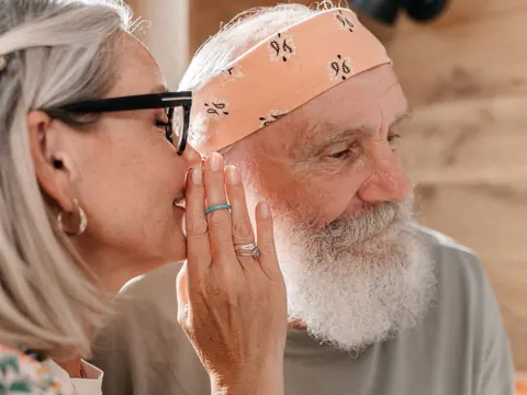 An older woman speaking into her husband's ear