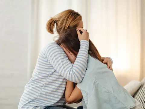 A mother hugging her upset daughter